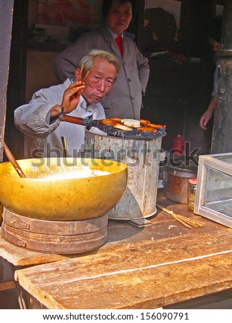 LUZHI, SHANGHAI, CHINA Ã¢Â?Â? OCTOBER 30: old guy cooking for tourists. The ancient village is a Shanghai tourist attraction with 100000 visitors per year. October 30, 2004 Luzhi, China.