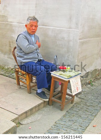 LUZHI, SHANGHAI, CHINA -Â?Â? OCTOBER 30: man selling peanuts at a street corner. The ancient village is a Shanghai tourist attraction with 100000 visitors per year. October 30, 2004 Luzhi, China.