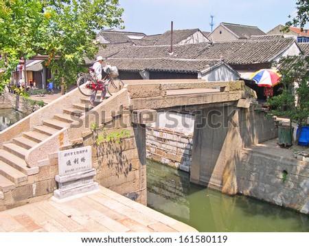 NANXUN, SHANGHAI, CHINA Ã¢Â?Â? AUGUST 28: lady crossing a canal on an old bridge. The Nanxun water village is Shanghai tourist attraction with 100000 visitors year. August 28, 2004,Nanxun, China