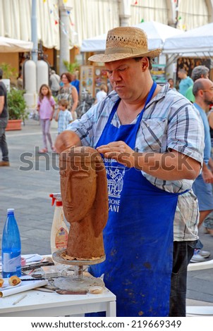 FAENZA, ITALY- SEPTEMBER 7, 2014: artist making a sculpture at the ceramic Sunday market. The market is very popular in the city and attracts thousands of people.