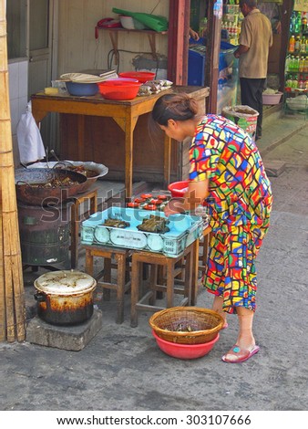 ZHUJIAJIAO, SHANGHAI-AUGUST 8, 2004: lady sells snacks in her shop in a village road. Zhujiajiao ancient village is a Shanghai tourist attraction with more than 1000000 visitors year.