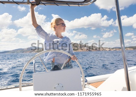 Similar – Foto Bild Attraktive blonde Skipperin, die das schicke Katamaran-Segelboot an einem sonnigen Sommertag auf ruhigem blauen Meerwasser steuert.