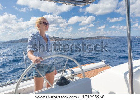 Similar – Foto Bild Attraktive blonde Skipperin, die das schicke Katamaran-Segelboot an einem sonnigen Sommertag auf ruhigem blauen Meerwasser steuert.