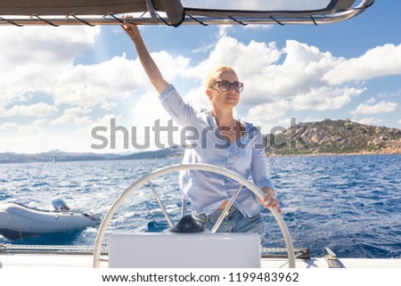 Similar – Foto Bild Attraktive blonde Skipperin, die das schicke Katamaran-Segelboot an einem sonnigen Sommertag auf ruhigem blauen Meerwasser steuert.