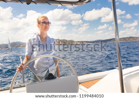 Similar – Foto Bild Attraktive blonde Skipperin, die das schicke Katamaran-Segelboot an einem sonnigen Sommertag auf ruhigem blauen Meerwasser steuert.