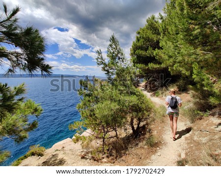 Similar – Image, Stock Photo Young active feamle tourist wearing small backpack walking on coastal path among pine trees looking for remote cove to swim alone in peace on seaside in Croatia. Travel and adventure concept.