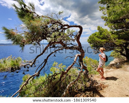 Image, Stock Photo Young active feamle tourist wearing small backpack walking on coastal path among pine trees looking for remote cove to swim alone in peace on seaside in Croatia. Travel and adventure concept.