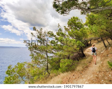 Similar – Image, Stock Photo Young active feamle tourist wearing small backpack walking on coastal path among pine trees looking for remote cove to swim alone in peace on seaside in Croatia. Travel and adventure concept.