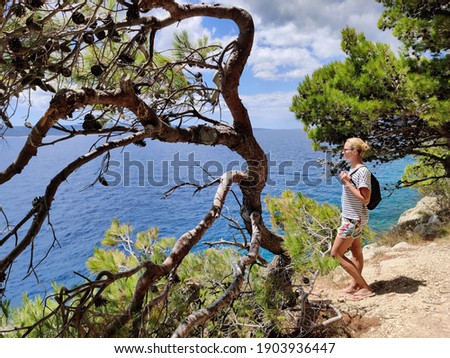 Similar – Image, Stock Photo Young active feamle tourist wearing small backpack walking on coastal path among pine trees looking for remote cove to swim alone in peace on seaside in Croatia. Travel and adventure concept.