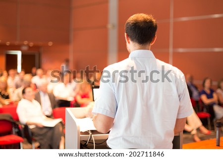 Academic professor lecturing at Conference. Audience at the lecture hall.