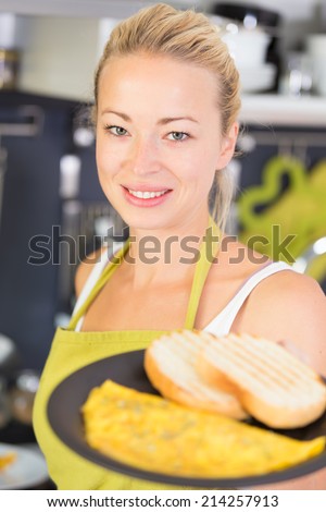 Young Woman Cooking. Healthy Mediterranean Breakfast - Home Made Egg Omlete Stuffed with Dried Tomatoes in Olive Oil and Cheese. Diet. Dieting Concept. Healthy Lifestyle. Cooking At Home.