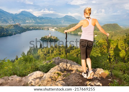 Young spoty active lady with hiking sticks admiring beautiful nature around Bled Lake in Julian Alps, Slovenia.