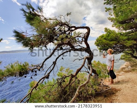 Similar – Image, Stock Photo Young active feamle tourist wearing small backpack walking on coastal path among pine trees looking for remote cove to swim alone in peace on seaside in Croatia. Travel and adventure concept.