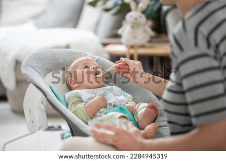 Similar – Image, Stock Photo Cheerful mother feeding adorable baby