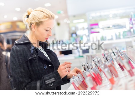 Beautiful blond lady testing  and buying cosmetics in a beauty store.