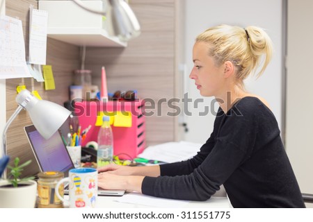 Business and entrepreneurship consept. Beautiful blonde business woman working on laptop in colorful modern creative working environment.