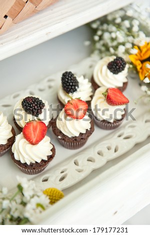 Cupcakes with a swirl of vanilla butter cream frosting and berries