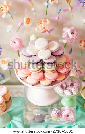 Dessert table with a large macaroons composition - pyramid in pink, decorated with flowers.
