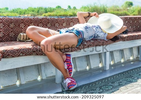 Attractive young lady in big white hat takes rest at recreational boat
