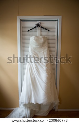 Beautiful wedding dress on hanger, in natural light from window