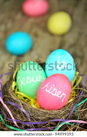 Jesus is Risen Easter eggs in nest on rustic wooden background