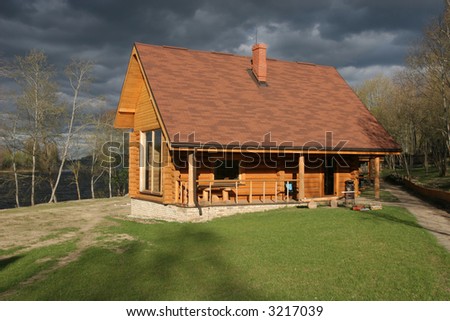 Traditional small wooden house near the river and stormy sky