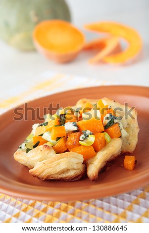 Pumpkin with blue cheese, leek and onion in puff pastry on plate