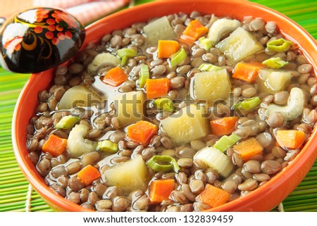 Lentil soup and pickled cucumbers in orange bowl