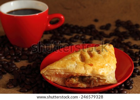 Black coffee in red cup ,  coffee bean and mushroom puff pastry.