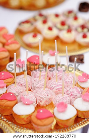 Pink pop cakes and cupcakes on golden plate
