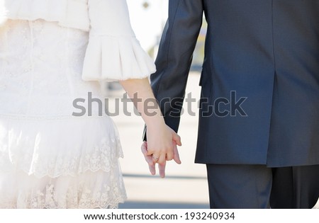 Bride and groom holding hands outdoors