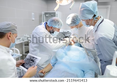 Surgeons and nurse during a dental operation.Anesthetized patient in the operating room.Installation of dental implants or tooth extraction in the clinic. General anesthesia during orthodontic surgery Stock foto © 