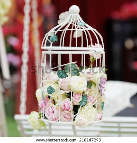 White cage with natural roses as decoration on wedding