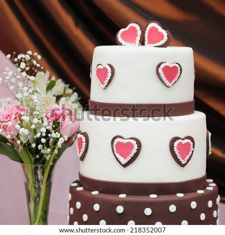 Delicious white and brown wedding cake decorated with pink hearts
