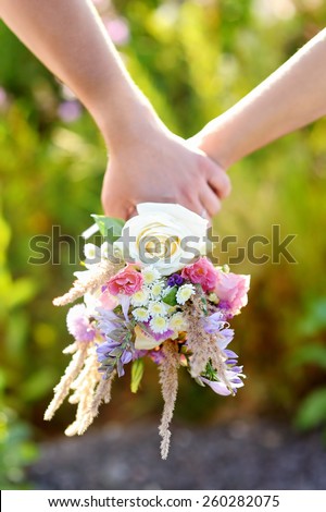 Female and male hands holding wild flowers bouquet