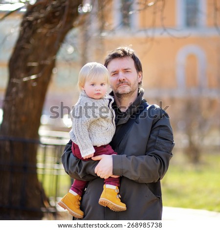 Middle age father with his toddler son walking and playing outdoors at the warm spring day