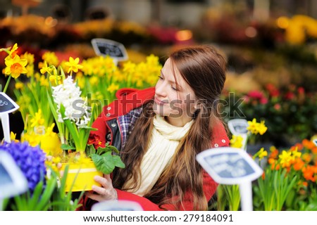 Beautiful young woman selecting fresh flowers at Parisian market