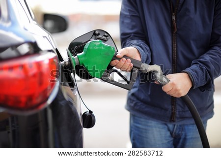 Pumping gas at gas pump. Closeup of man pumping gasoline fuel in car at gas station.