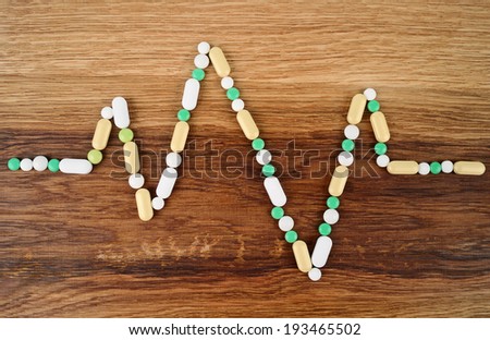 Heart rate graph line made from pills placed on wooden background