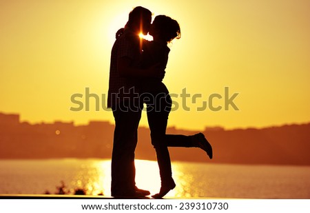 couple in love back light silhouette at lake orange sunset