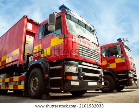 Two red fire truck emergency vehicles. The fire engines are with ladders, firefighting apparatus and water to save lives, suppress wildfire, extinguish building fires and assist vehicle collisions. Stockfoto © 