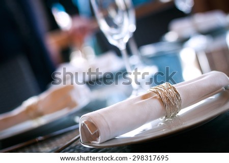 A dining table scene with focus on the napkin ring with plenty of copy space. A shallow focus/abstract background is used, offering plenty of copy space.