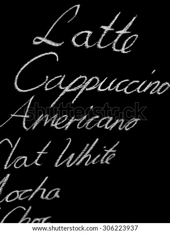 Coffee menu with a variety of coffee drinks to choose from (Latte, Cappuccino, Americano). Stylized in hand drawn writing using white chalk on a black chalkboard. Focus is on the word \'Americano\'.