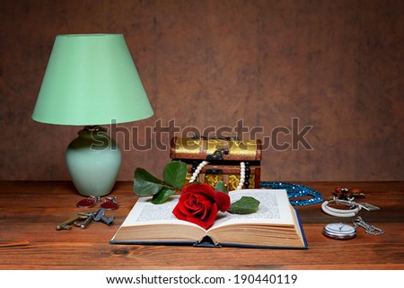 Desk lamp, jewelry and red rose on the table
