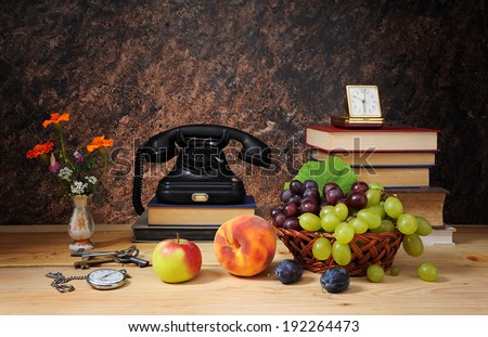 Old phone, fruit and books on the table