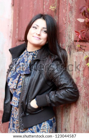 Lovely face of young woman over old wooden door at autumn season