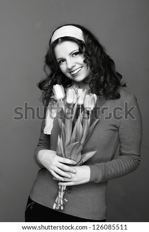 Studio black and white image of young woman with tulips/Beautiful young girl with a bouquet of spring flowers on Holiday theme