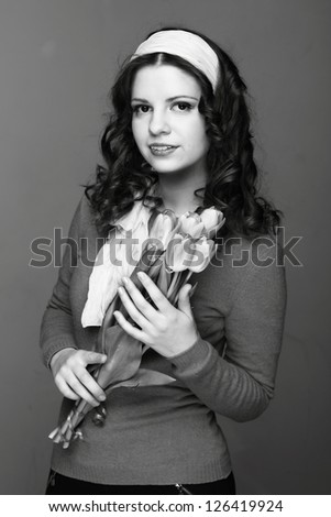 Studio black and white image of beautiful young woman with fresh tender tulips/European young girl with a bouquet of spring flowers