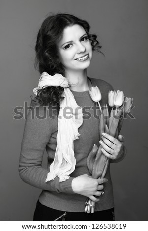 Black and white image of beautiful young woman with fresh tender tulips on Beauty and Fashion theme