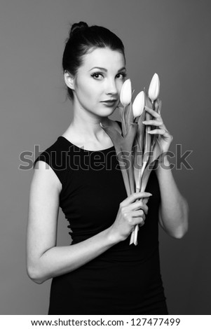 Studio black and white image young girl with a bouquet of spring flowers